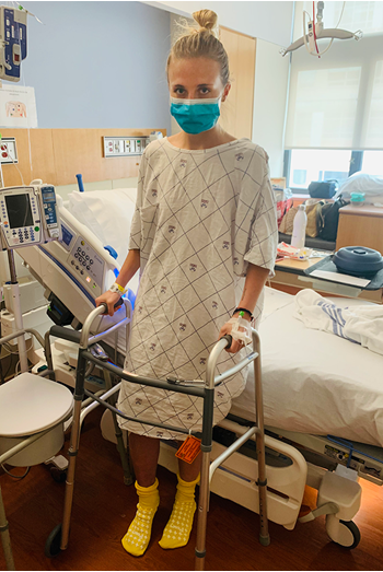 Erin in hospital gown using walker